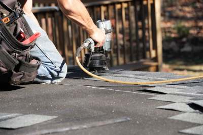 Homme occupé à poser du roofing sur un toit plat